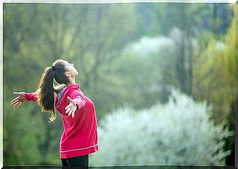 Woman doing breathing exercises with open arms.