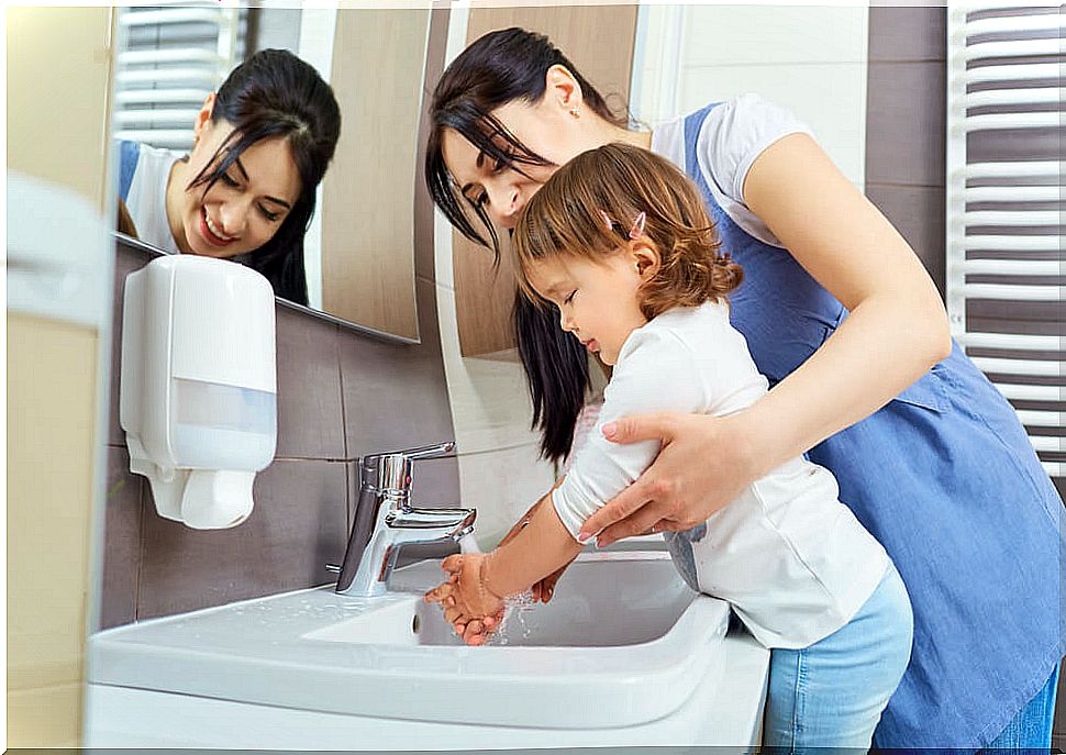 mother teaching daughter to wash her hands