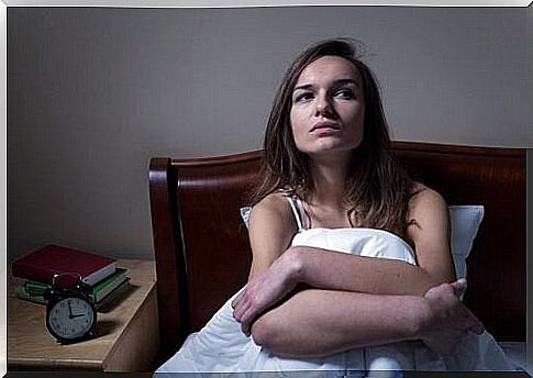 Woman suffering from panic attacks sitting on bed.